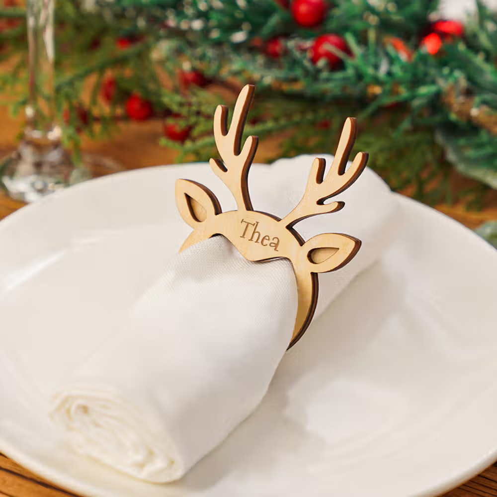 An engraved wooden deer napkin ring keeps white napkins arranged in a plate
